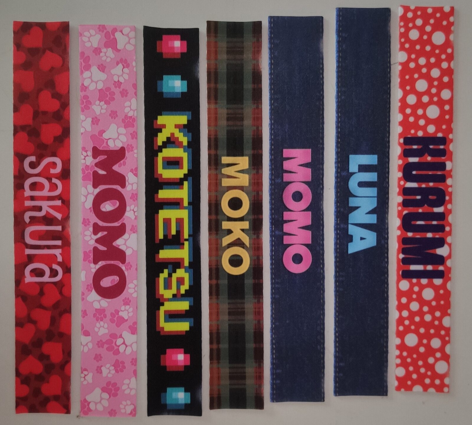Seven short printed fabric strips in red, pink, black, plaid, navy and white patterns with names like Momo, Kotetsu and Luna.