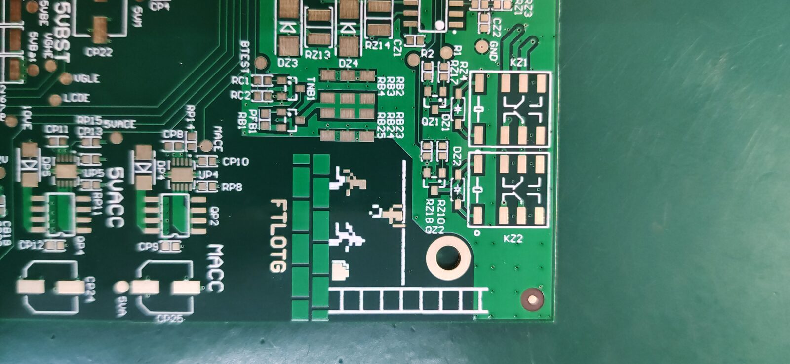Close-up of a green circuit board with a pixel-art running figure and ladder on its surface.